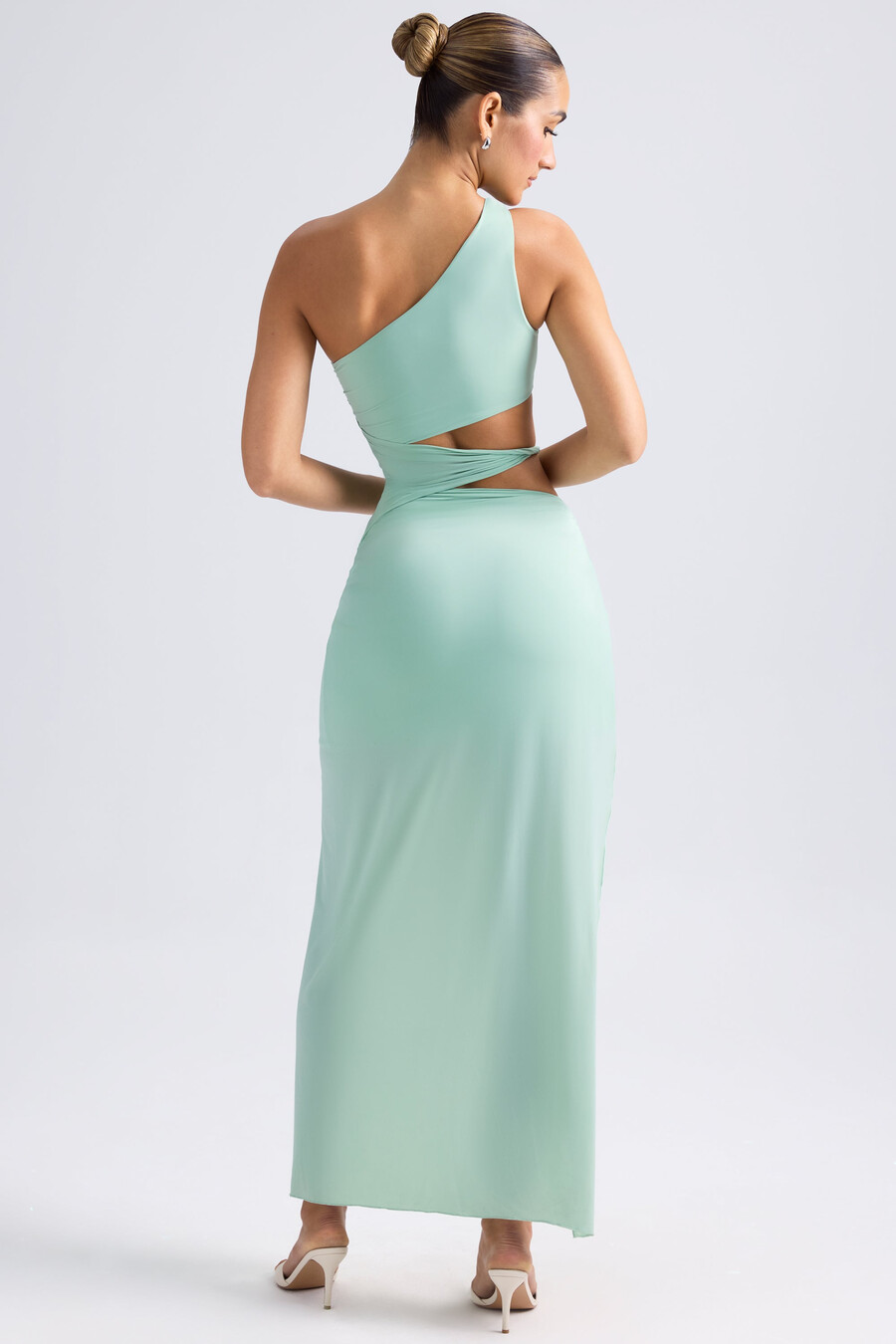 maxi-jurk met één schouder gedrapeerd en met uitsnijdingen in pastelgroen.