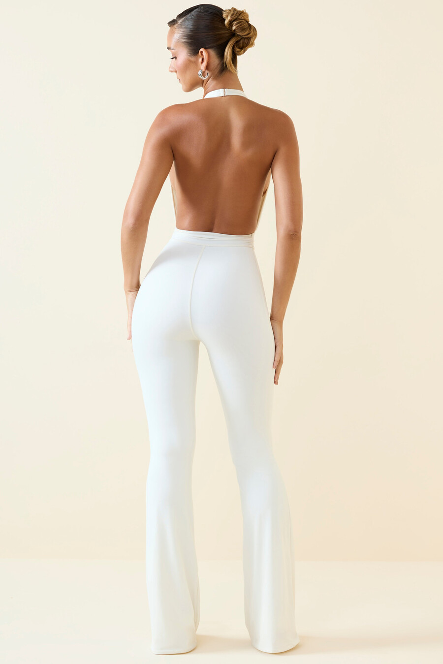 jumpsuit met halternek uitlopende rok en uitsparingen in vanillekleur.